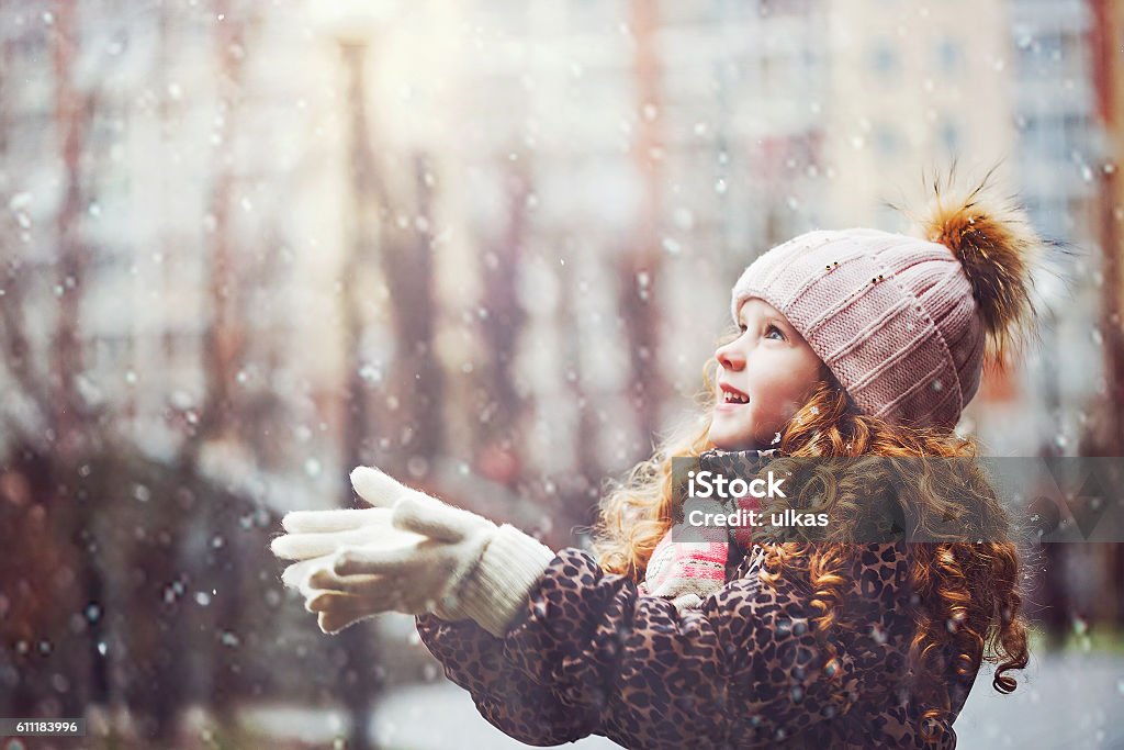 Kleines Mädchen streckt ihre Hand, um fallende Schneeflocken zu fangen. - Lizenzfrei Kind Stock-Foto