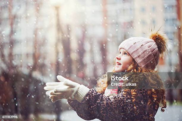 Niña Estira La Mano Para Atrapar Los Copos De Nieve Que Caen Foto de stock y más banco de imágenes de Niño