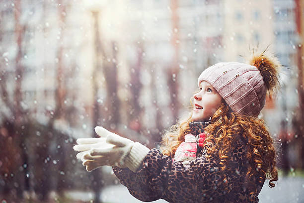 Little girl stretches her hand to catch falling snowflakes. Cute little girl stretches her hand to catch falling snowflakes. First snow. children in winter stock pictures, royalty-free photos & images