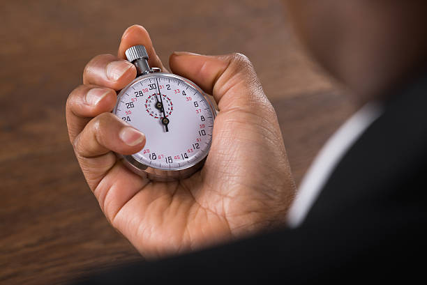 homme d’affaires tenant un chronomètre - clock time clock hand urgency photos et images de collection