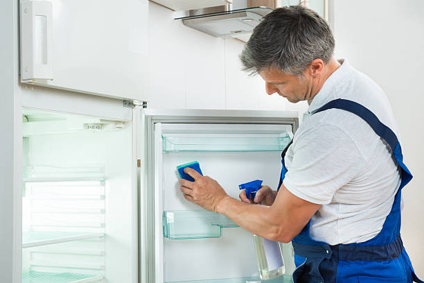 istock Janitor Cleaning Refrigerator At Home 611185326