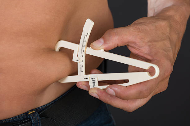 istock Shirtless Man Measuring Stomach Fat With Caliper 611185672