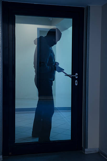 istock Burglar Using Crowbar To Open Glass Door 611185834