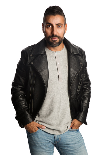 Trendy man standing against a white background wearing a black jacket and jeans, feeling relaxed and comfortable.