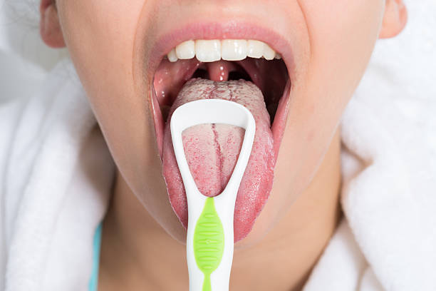 Woman Cleaning Tongue Closeup of young woman cleaning tongue with cleaner tongue scraper stock pictures, royalty-free photos & images