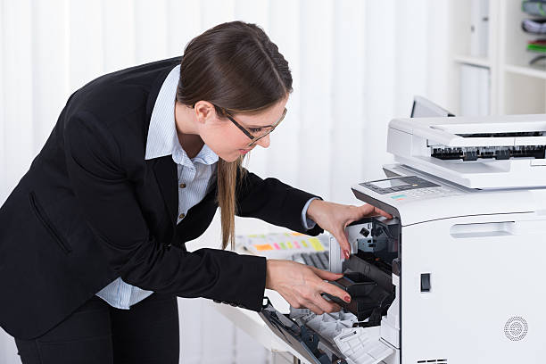 istock Businesswoman Fixing Copy Machine 611189128