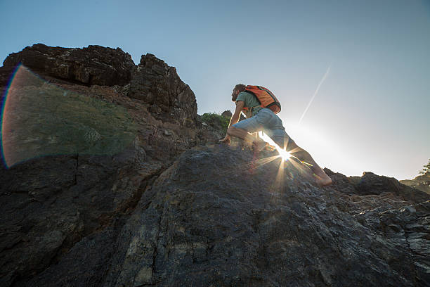 istock Caucasian male climbs steep rock, towards sunlight 611193032