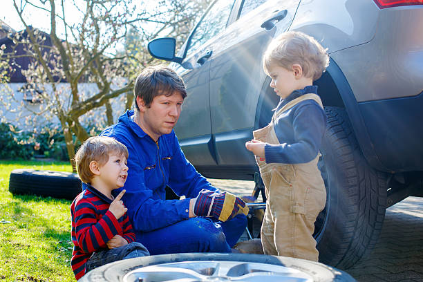 istock Little kid boys and his father changing wheel on car 611193612