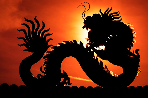 A silhouette image of chinese dragon statue in dragon chinese temple. Sun dragon position at dragon eye. Yellow dragon.
