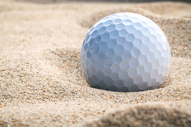 Close up golf ball in sand bunker .