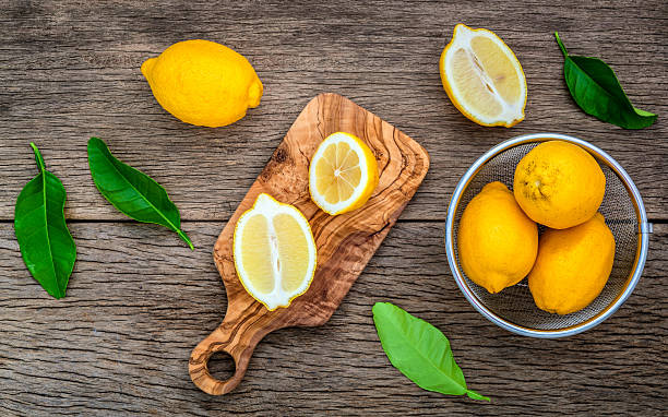 istock Fresh lemons and  lemons leaves on rustic wooden background. 611197198