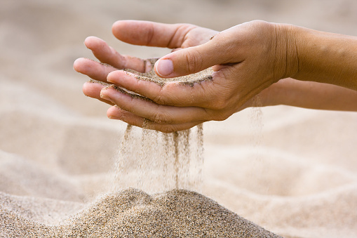 sand running through fingers of woman in the beach
