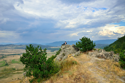 Tourist on the rock in Pirin mountain looking at the fields near Dobrinishte. Bulgaria, Eastern Europe