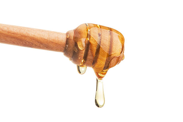 istock Honey dripping from a wooden dipper on isolate white background. 611200332