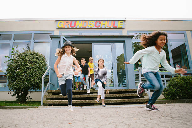 Los estudiantes de la escuela primaria se quedellan sin escuela a Schoolyard - foto de stock