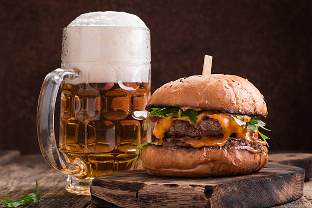 fresh hamburger with a beer on a wooden table. - beer hamburger american culture beef imagens e fotografias de stock