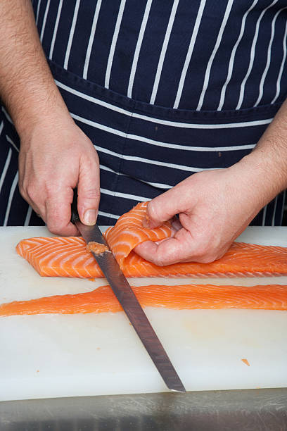 istock Chef cutting salmon fish on fillets with knife 611210044