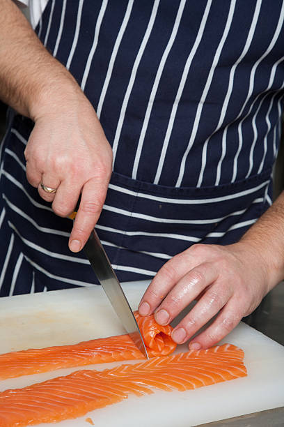 istock Chef cutting salmon fish on fillets with knife 611210118