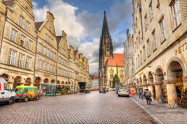 Prinzipalmarkt mainstreet of Munster, Germany Munster, Germany - December 23, 2015: People walk in the early morning in the Prinzipalmarkt street lined with historical buildings and the Saint Lamberti church and a chrismas tree in Munster, Germany on December 23, 2015 munster stock pictures, royalty-free photos & images