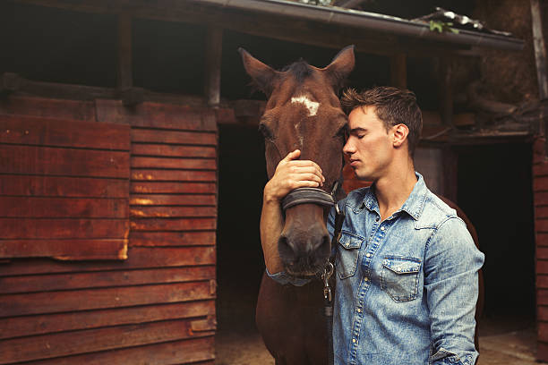 istock Young man stroking a brown horse. 611215572
