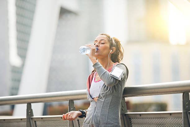 mujer corredora está teniendo un descanso y beber agua - financial district audio fotografías e imágenes de stock