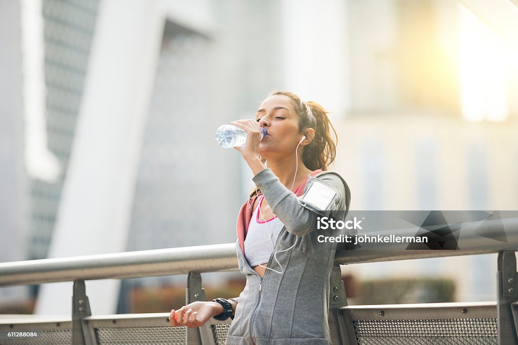 Woman runner is having a break and drinking water Drinking Stock Photo