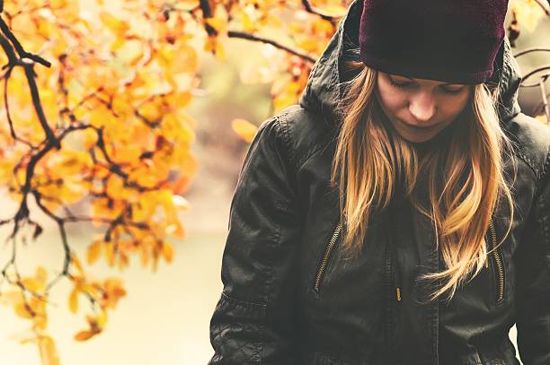 Photo of Sad Woman walking in park with autumn leaves on background