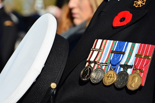 Victoria BC, Canada, November 11th 2014.A war veteran at the ceremonial Remembrance day displays his medals of valor a poppy and the removing of his hat showing respect for fallen soldiers.