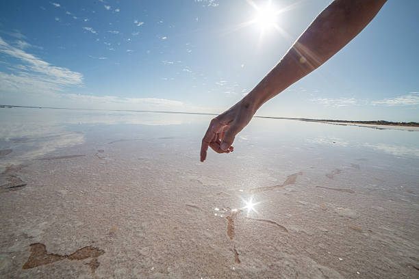 istock Finger touches surface of salted lake 611292396