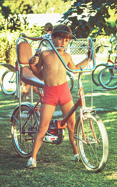 Vintage boy with his bicycle Vintage photo from the seventies featuring a young boy with his bicycle in a summer day. retro bicycle stock pictures, royalty-free photos & images