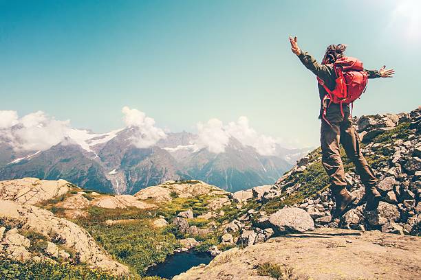 istock Happy Man with red backpack jumping hands raised mountains landscape 611294064