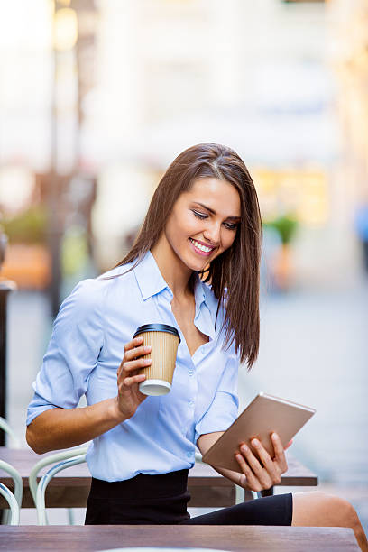 istock Beautiful young business woman using tablet and drinking coffee 611294256