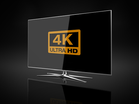 UHD 4K Smart Tv standing on black reflective background.  There is 4K Logo on the display. Side view. Clipping path is included.