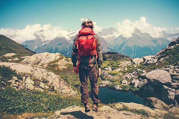 istock Happy Man with red backpack jumping levitation mountains landscape 611294802