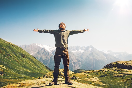 Bearded Man traveler hands raised outdoor Travel Lifestyle happiness concept mountains landscape on background active vacations sunny day