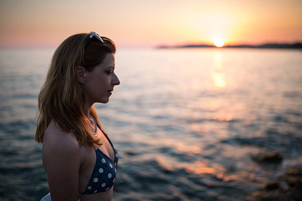 istock woman on the beach enjoying at sunset 611297520
