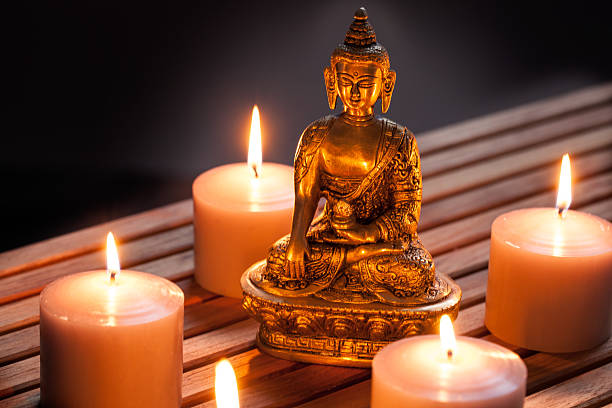 istock Bronze Buddha with warm lighted candles over wooden background 611298424