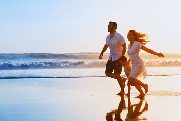 family - father, mother, baby run on sunset beach - women hawaii islands beach beauty in nature imagens e fotografias de stock