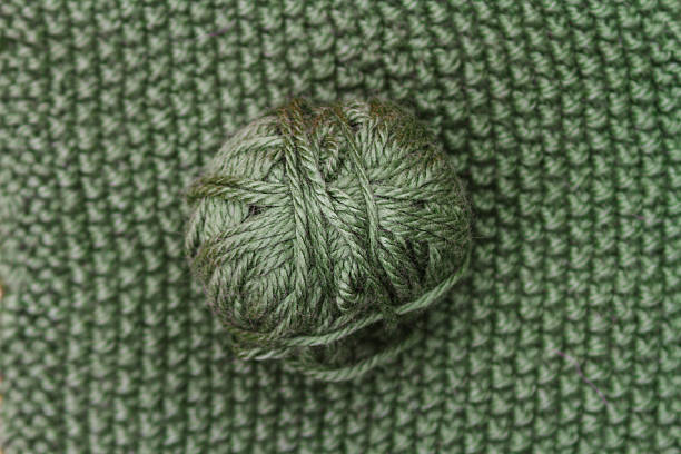 istock Green ball of wool on green cloth woven wool 611304708