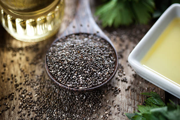 Wooden spoon oil chia seeds Wooden spoon with chia seeds (salvia hispanica) and oil chia seed photos stock pictures, royalty-free photos & images