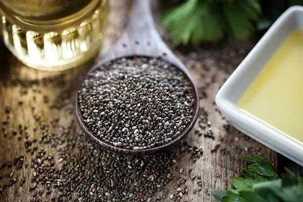 Wooden spoon with chia seeds (salvia hispanica) and oil