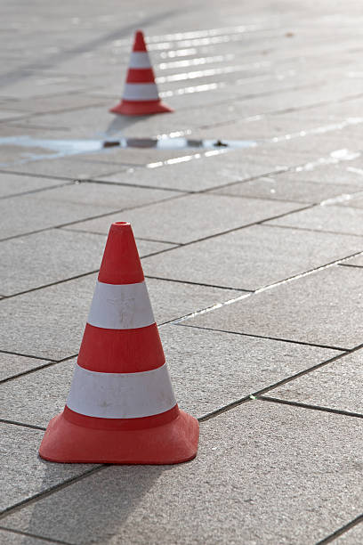 istock traffic cones  on a paved road with a puddle 611310176