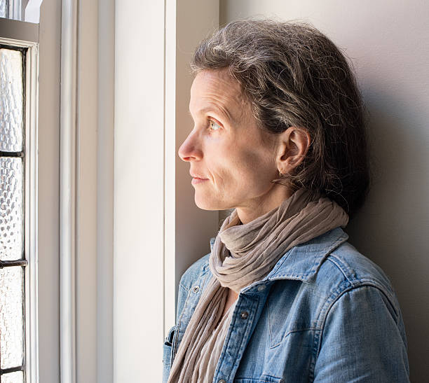 istock Profile of middle aged woman at window 611312138