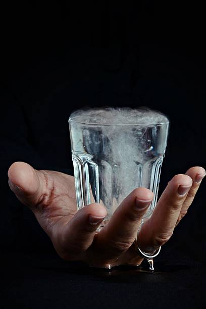 Glass of water in the hand on the dark background