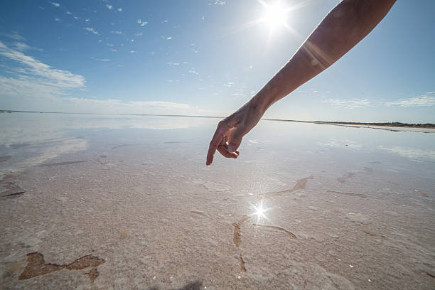 istock Finger touches surface of salted lake 611313120