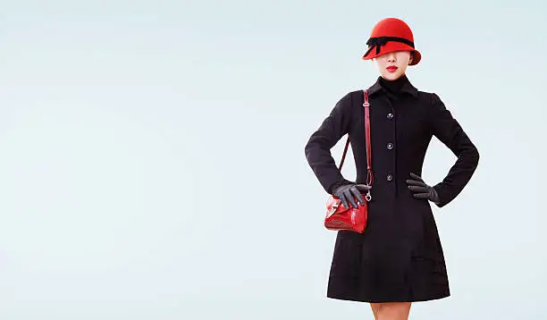 Wool black coat,red shoulder bag,hat and lipstick. Vintage retro style fall winter look on the light blue background.