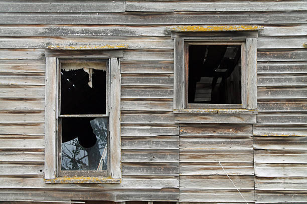 istock Two Broken Windows in a Dilapidated Brown Wooden House 611316804