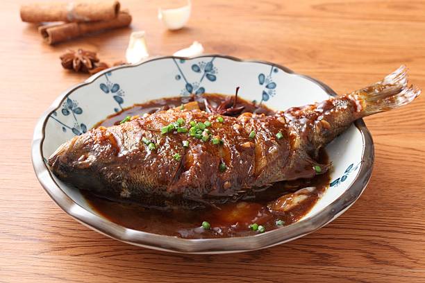 istock Fried fish on chinese plate on wooden table in restaurant 611317688