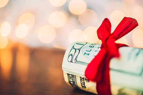 christmas cash. wad of american currency tied with red ribbon - money roll fotos imagens e fotografias de stock
