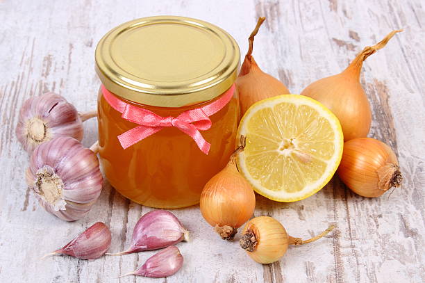 Honey in glass jar, onion, lemon and garlic, healthy nutrition stock photo
